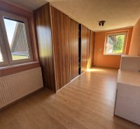 A room in a family house with a wooden decor floor and a built-in wardrobe.
