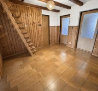 Interior of a family house with wooden paneling, staircase, and ceramic flooring.