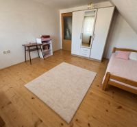 A room in a family house with a bed, a wardrobe, and a floor with a wooden decor.