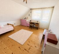 A room in a family house with wooden decor, pink furniture, and a writing desk.