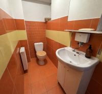 A bathroom with tiles and a sink in a family house with orange and yellow tiles.