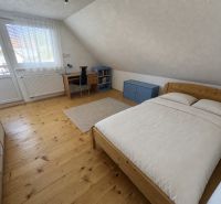 Attic room in a family house with a wooden decor floor and a desk.