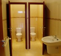 Interior of offices with two toilets and a sink on light tiles.