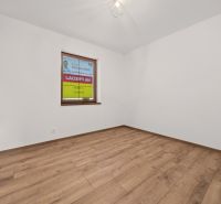 A room with white walls and a wood-patterned floor in a family house.