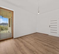 A room in a family house with white walls and a wooden decor floor.
