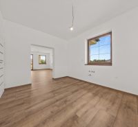 The interior of a family house with a wooden decor floor and large windows in the rooms.