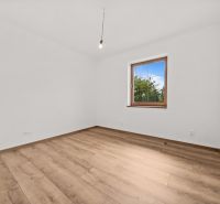 A room in a family house with white walls and a wooden decor floor.
