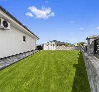The garden of a family house in Nitra with a lawn and stone paving by the wall.