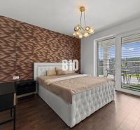 A bedroom with wood-patterned flooring, a quilted headboard, and a view of the terrace.