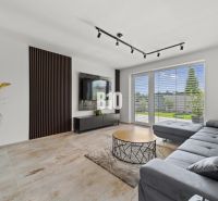 Living room in a family house with a sofa, television, and a window with a view.