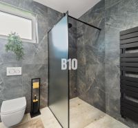 A bathroom in a family house with a black radiator and a shower enclosure.