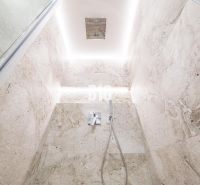 Shower enclosure with light stone tiles in a 3-room apartment.