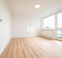 A room in a 3-room apartment with a wooden decor floor and large windows.