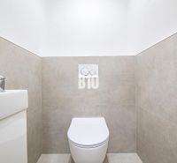 Bathroom in a 3-room apartment with toilet and sink, simple tiles on the walls.
