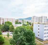 View from a 3-room apartment in Nitra of panel buildings and a parking lot with cars.