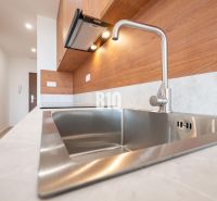 Modern kitchen in a 3-room apartment with a stainless steel sink and wooden decor.