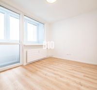 A spacious room in a 3-room apartment with large windows and a wooden decor floor.