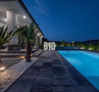 A family house in Nitra with a swimming pool and an illuminated garden in the evening.