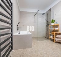 A bathroom in a family house with a bathtub, a shower corner, and a towel rack.