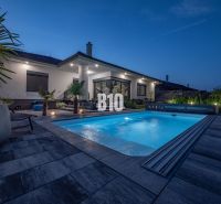 A family house in Nitra with a swimming pool and garden seating in an evening atmosphere.
