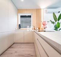 A kitchen in a family house with a wooden decor floor, white cabinets, and flowers.