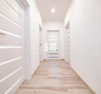 A bright hallway in a family house with a wooden decor floor and white doors.