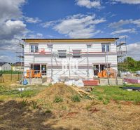 Construction of a family house in Nitra with scaffolding under construction and materials on the site.