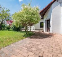 A family house in Nitra with a terrace, garden, and trees on a grassy area.