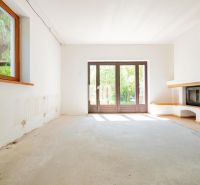 Living room in a family house with spacious windows and a fireplace, without floor covering.