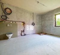 A construction space with a toilet installation and a window in a family house.