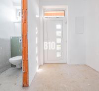 White hallway of a family house with entrance doors and a bathroom on the left.