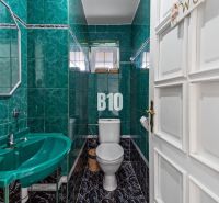 A bathroom in a family house with green tiles and a sink.