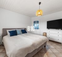 Bedroom in a family house with a bed, television, and nightstand.
