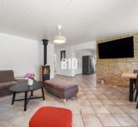 Living room in a family house with a fireplace and a television on a stone-clad wall.