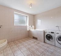 A bathroom in a family house with a washing machine, bathtub, and shower.