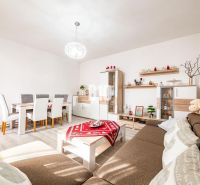 Living room with a dining table, wood-patterned floor, and a brown sofa in a family house.