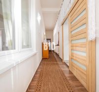 A hallway in a family house with a wooden decor floor and sliding doors.
