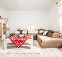 Living room in a family house with a corner sofa, wooden decor, and colorful placemats.