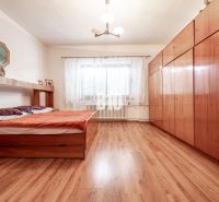Bedroom in a family house with a bed, wardrobe, and wooden decor flooring.