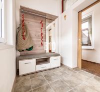 Entrance hall in a family house with a coat rack, seating, and tiled floor.