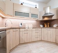 A kitchen in a family house with a wooden decor floor and light furniture.