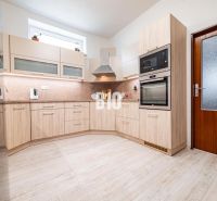 A kitchen in light tones with a wood-patterned floor and built-in appliances.