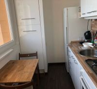 A small kitchen with a wooden table, white cabinets, and a floor with a wooden design.