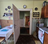 A kitchen in a 2-room apartment with a gas stove, table, carpet, and decorations on the walls.