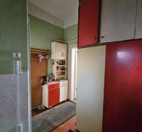 The entrance hallway of a 2-room apartment with green walls and cabinets in red and white colors.