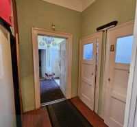 A hallway with an entrance to a room and a floor with a wooden decor in a 2-room apartment.
