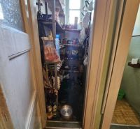 Storage space in a 3-room apartment with shelves, various items, and canned goods.