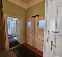 A hallway with pale walls and doors in a 2-room apartment, a floor with a wooden decor.