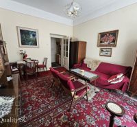 Living room in a 2-room apartment with a carpet and wooden furniture, paintings on the walls.