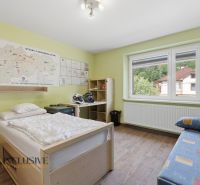 A room in a family house with a map on the wall, a bed, and a wooden decor floor.
